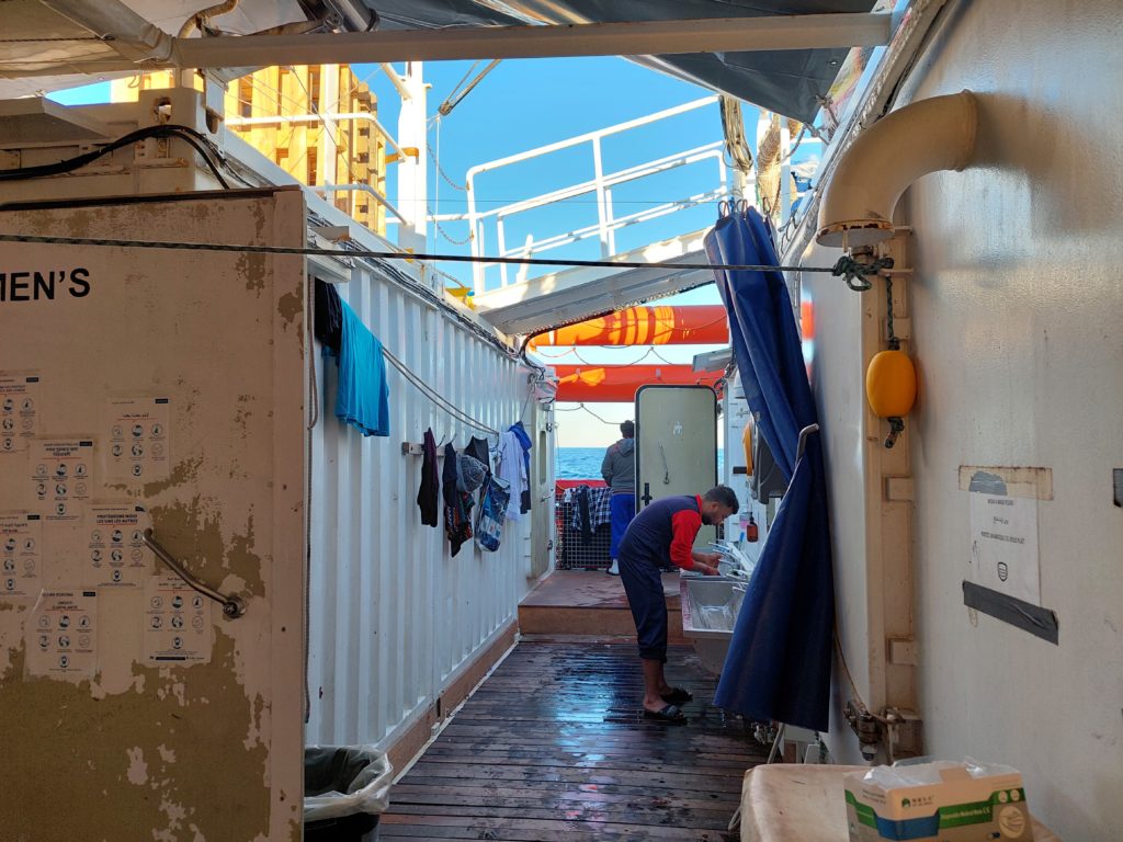 Waschbereich an Bord der Ocean Viking abgebildet. Eine Person wäscht sich die Hände am Waschbecken.